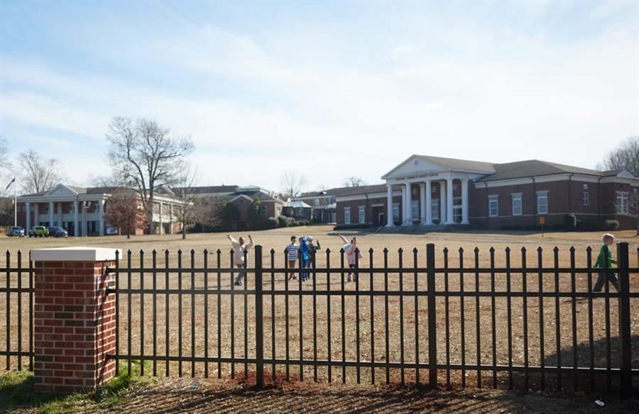  A view through a black iron fence of the Alabama School for the Blind campus.